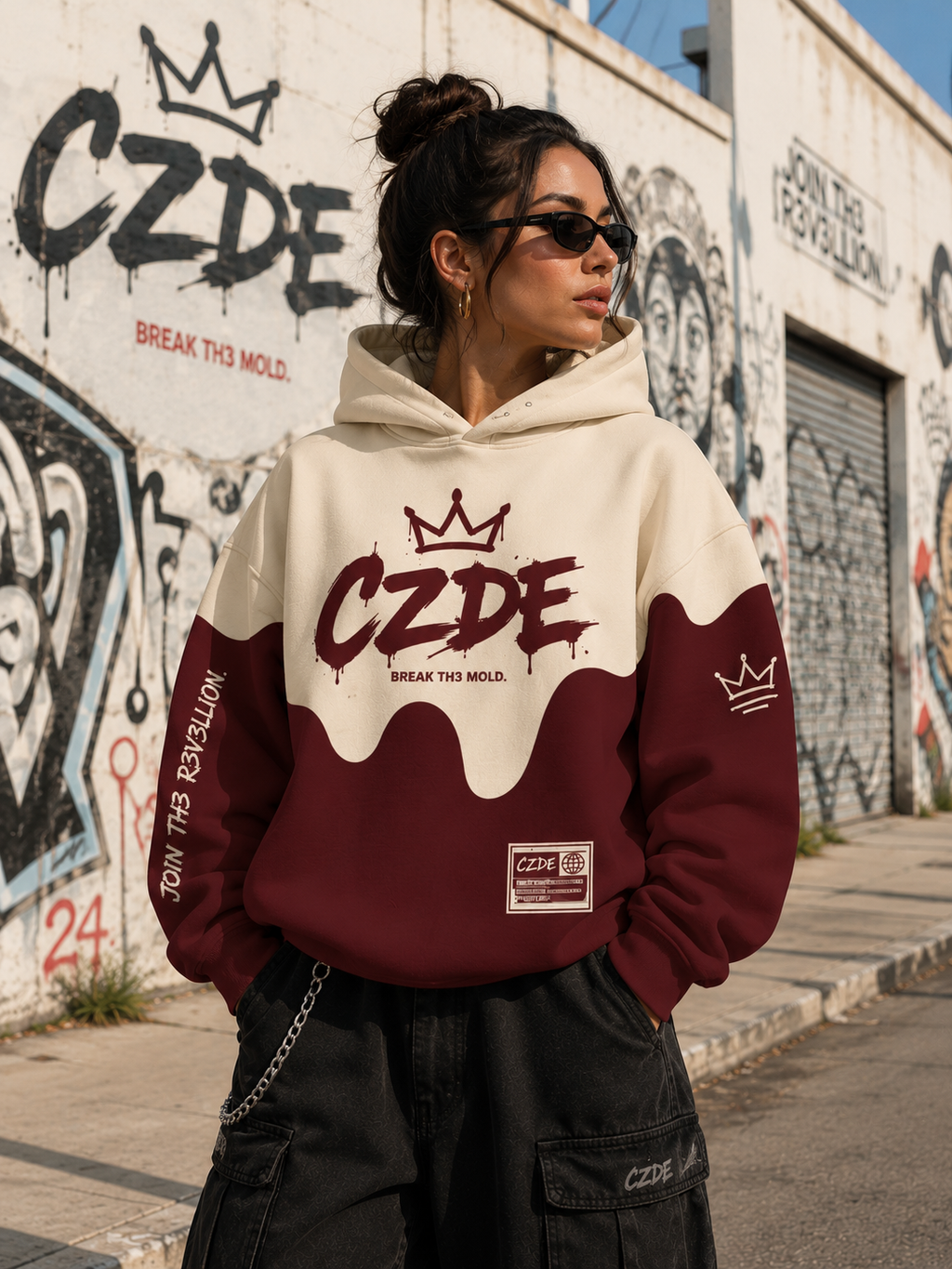 Female model wearing CZDE Burgundy Drip Hoodie – front view, CZDE graffiti wall street editorial with BREAK TH3 MOLD background