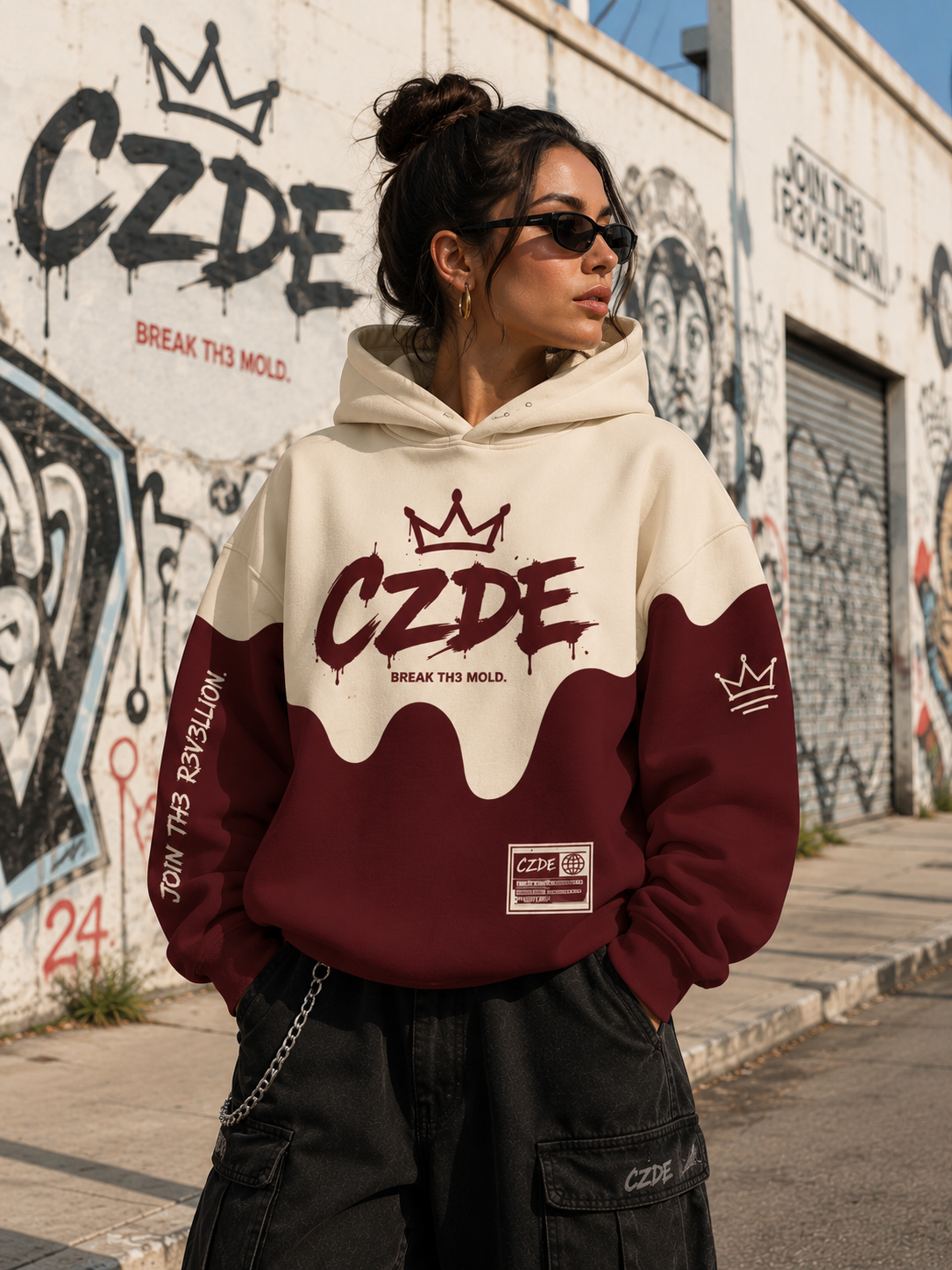 Female model wearing CZDE Burgundy Drip Hoodie – front view, CZDE graffiti wall street editorial with BREAK TH3 MOLD background