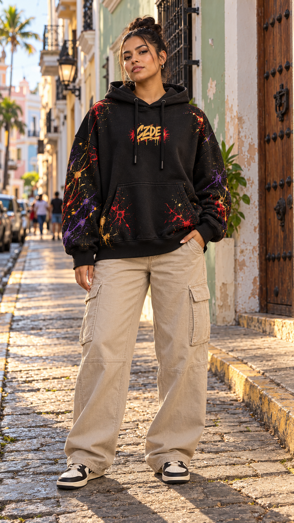 Black oversized hoodie with small chest graphic and colorful paint-splatter sleeves
